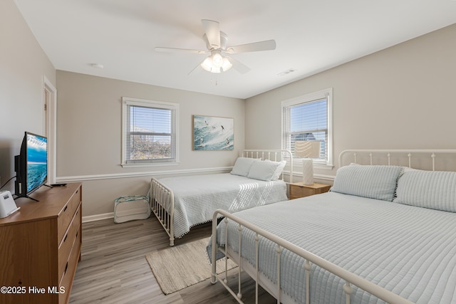 bedroom featuring a ceiling fan, light wood-type flooring, baseboards, and multiple windows