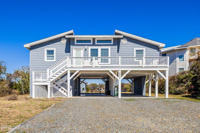 raised beach house featuring a carport, stairway, and driveway