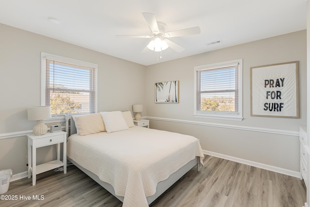 bedroom featuring visible vents, light wood-type flooring, multiple windows, and baseboards