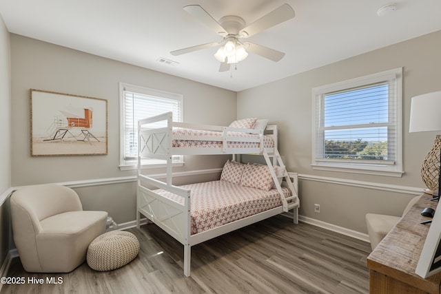 bedroom with visible vents, baseboards, a ceiling fan, and wood finished floors