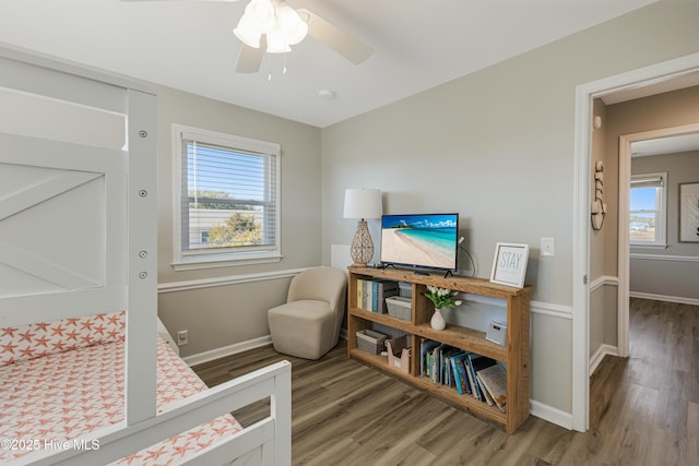 bedroom with multiple windows, baseboards, and wood finished floors