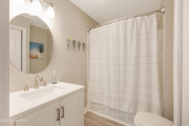bathroom with toilet, wood finished floors, vanity, and shower / tub combo with curtain