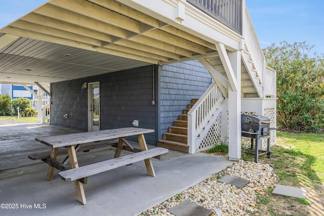 view of patio featuring grilling area, an attached carport, outdoor dining area, and stairs