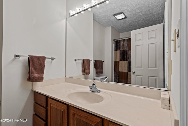 full bathroom with a shower with curtain, toilet, vanity, and a textured ceiling