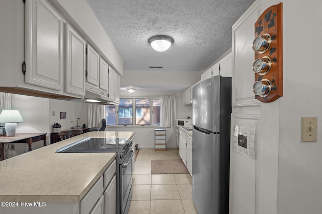 kitchen featuring light countertops, electric range oven, freestanding refrigerator, light tile patterned floors, and white cabinets