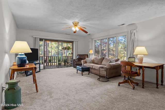 living area featuring a ceiling fan, carpet floors, a textured ceiling, and visible vents