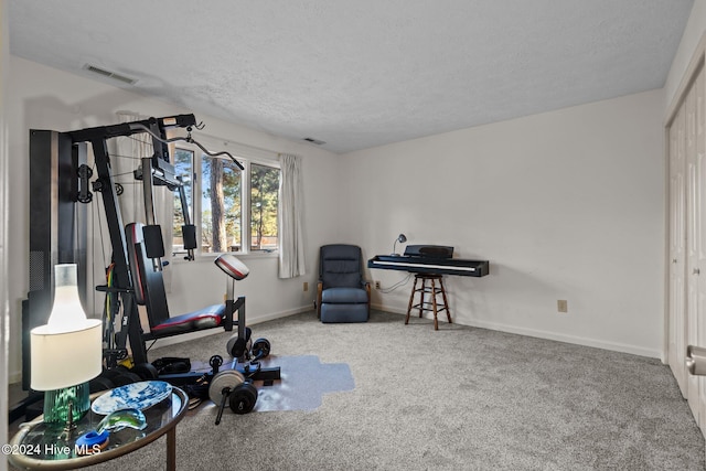 exercise area with visible vents, carpet, baseboards, and a textured ceiling