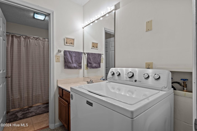 clothes washing area with washer / clothes dryer, tile patterned flooring, laundry area, and a textured ceiling