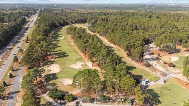 drone / aerial view with view of golf course and a wooded view