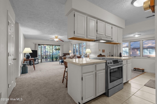kitchen with white cabinetry, light countertops, open floor plan, stainless steel range with electric stovetop, and under cabinet range hood
