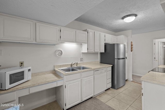 kitchen featuring white cabinetry, light countertops, a sink, and white appliances