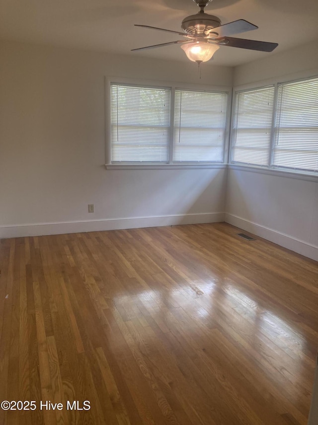 empty room featuring baseboards, ceiling fan, and light wood-type flooring