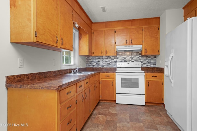 kitchen with white appliances, tasteful backsplash, under cabinet range hood, a sink, and dark countertops