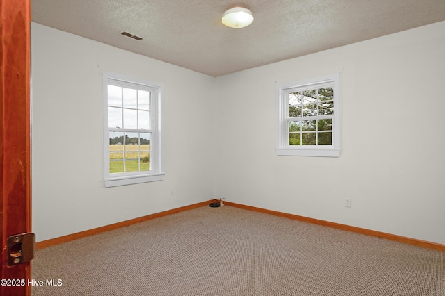 spare room featuring baseboards, carpet, visible vents, and plenty of natural light