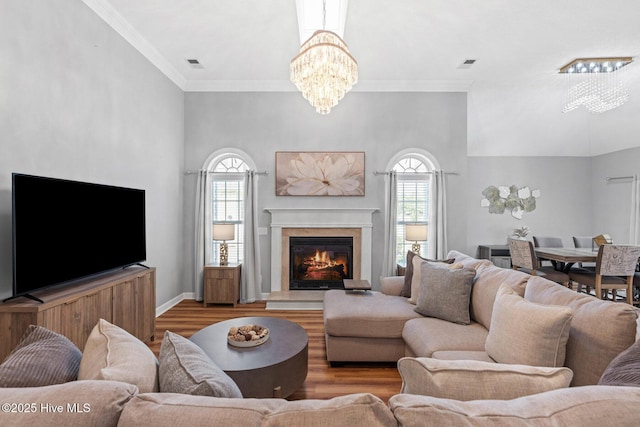1096 Rutledge Ct NW, Calabash, NC 28467 - living room featuring a chandelier, wood finished floors, a glass covered fireplace, baseboards, and crown molding