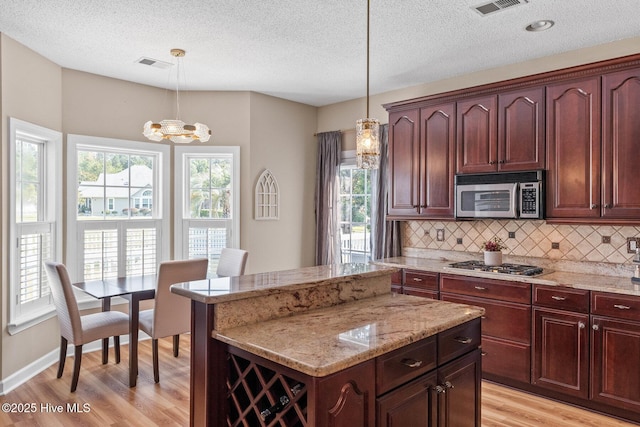 1096 Rutledge Ct NW, Calabash, NC 28467 - kitchen featuring stainless steel appliances, light wood-type flooring, decorative backsplash, a center island, and a textured ceiling
