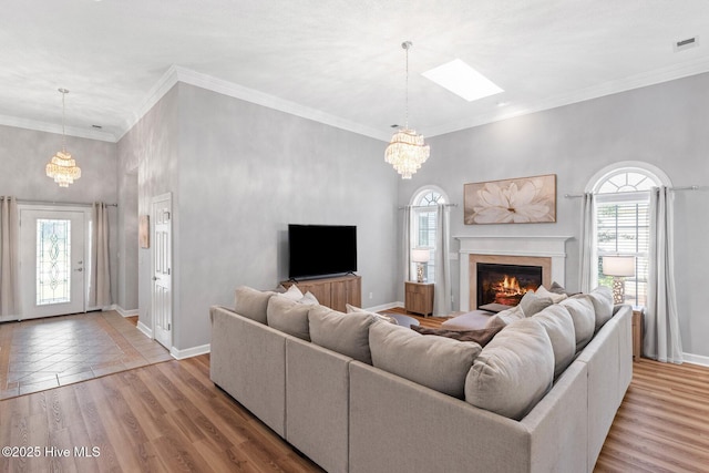 1096 Rutledge Ct NW, Calabash, NC 28467 - living area featuring a chandelier, a glass covered fireplace, baseboards, a skylight, and crown molding