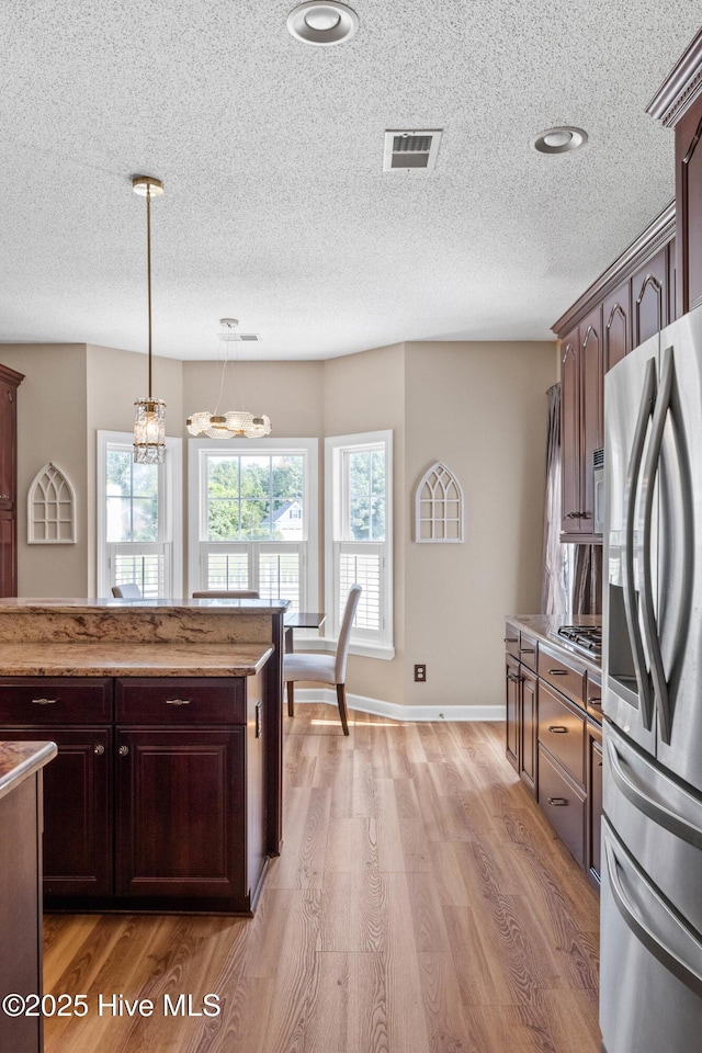 1096 Rutledge Ct NW, Calabash, NC 28467 - kitchen with stainless steel fridge with ice dispenser, light wood-style floors, a textured ceiling, hanging light fixtures, and dark brown cabinets