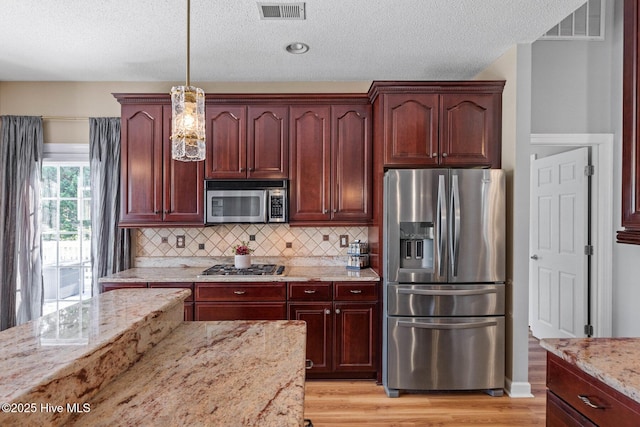 1096 Rutledge Ct NW, Calabash, NC 28467 - kitchen featuring stainless steel appliances, light stone countertops, light wood-style floors, dark brown cabinets, and a textured ceiling