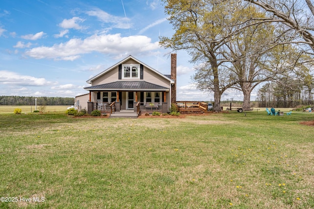 view of front of property featuring covered porch, a chimney, a front lawn, and metal roof