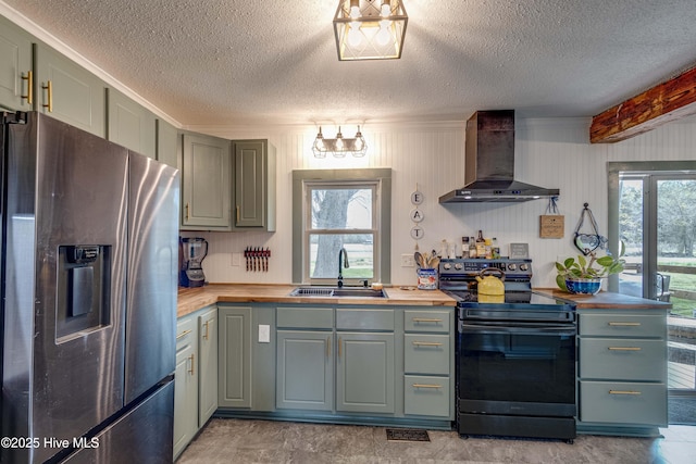 kitchen featuring a sink, stainless steel refrigerator with ice dispenser, wall chimney range hood, black electric range, and wood counters