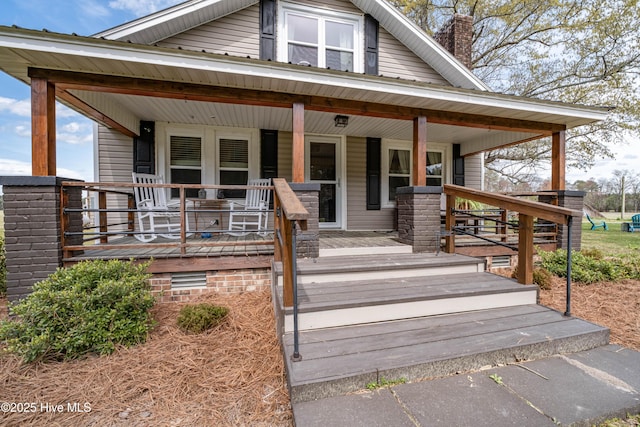 view of front of house featuring a chimney and a porch