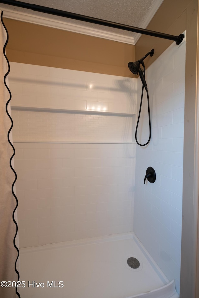 bathroom featuring a tile shower, ornamental molding, and a textured ceiling