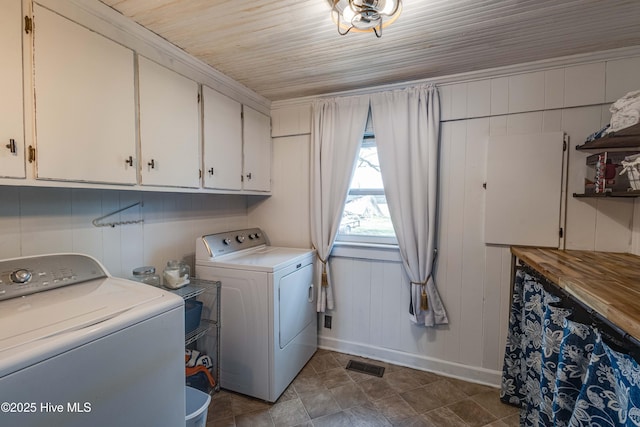 clothes washing area featuring wooden ceiling, cabinet space, visible vents, and washer and clothes dryer