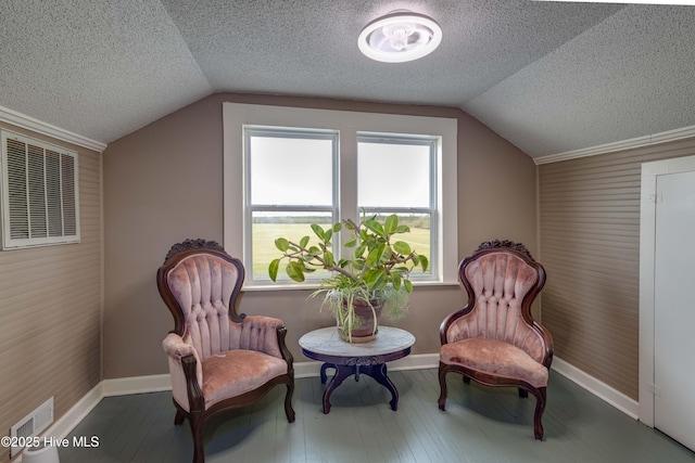 living area featuring wood-type flooring, vaulted ceiling, and visible vents