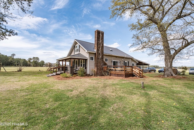 back of property with a lawn, metal roof, a deck, and a chimney