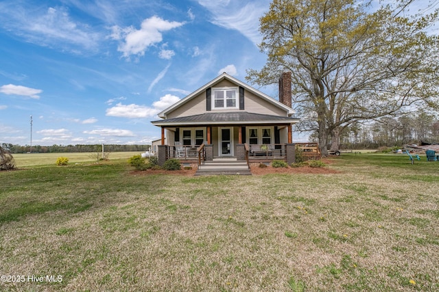 view of front of property with a front lawn, metal roof, a porch, and a chimney