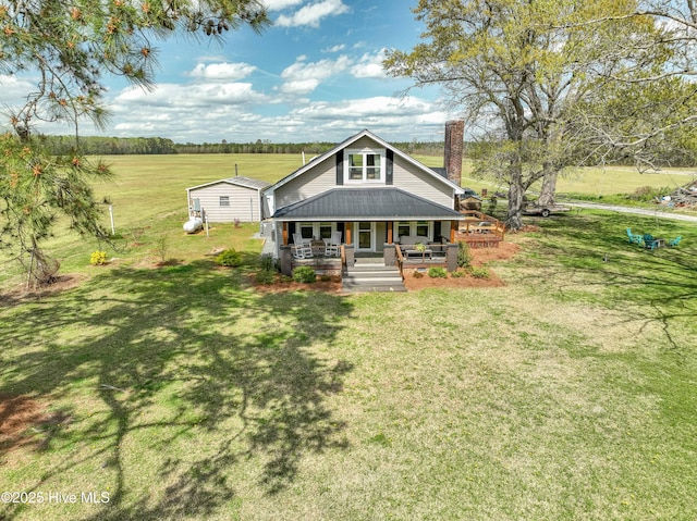 view of front facade with covered porch, metal roof, and a front lawn