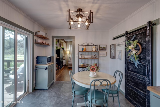 dining room with a notable chandelier, crown molding, and a barn door
