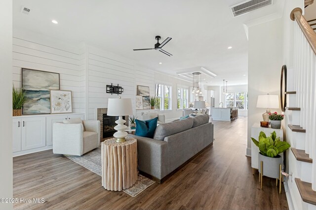 living area featuring a ceiling fan, a fireplace, wood finished floors, visible vents, and recessed lighting