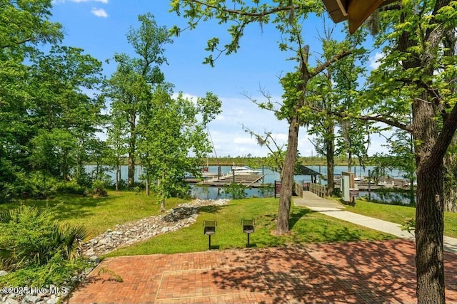view of property's community featuring a water view, a yard, and a dock