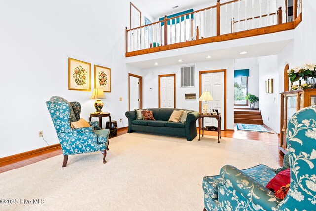living room featuring visible vents, baseboards, recessed lighting, wood finished floors, and a high ceiling