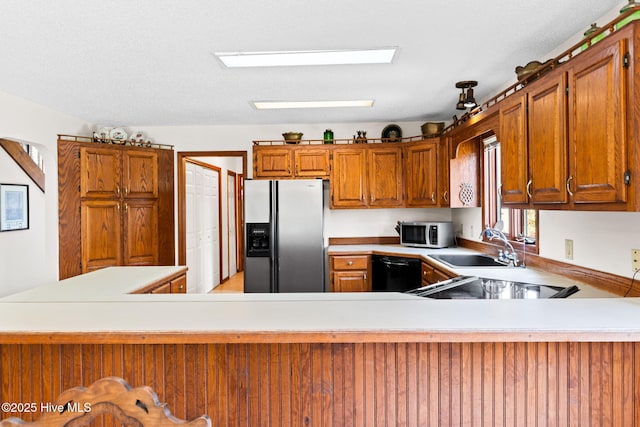 kitchen featuring stainless steel microwave, light countertops, fridge with ice dispenser, dishwasher, and a sink