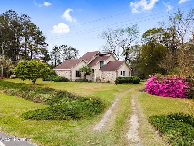 view of property exterior with driveway, a yard, and stone siding
