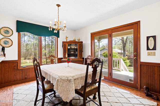 2781 Exum Rd NW, Ash, NC 28420 - dining room featuring a wainscoted wall, a chandelier, light wood-style flooring, wood walls, and a textured ceiling