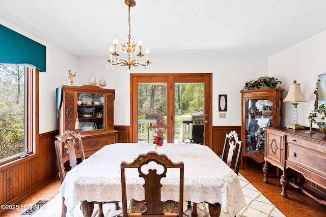 dining space with plenty of natural light, a notable chandelier, and wainscoting