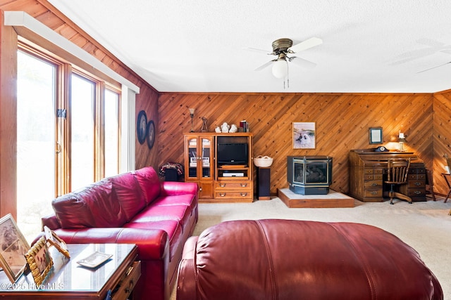 living area with wood walls, ceiling fan, and carpet floors