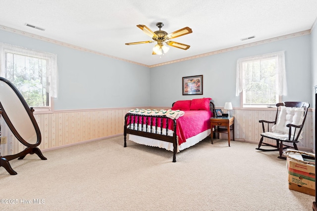 bedroom featuring visible vents, wainscoting, multiple windows, and carpet