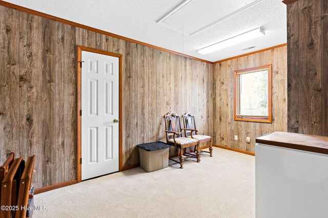 living area featuring wood walls, attic access, carpet flooring, and a textured ceiling