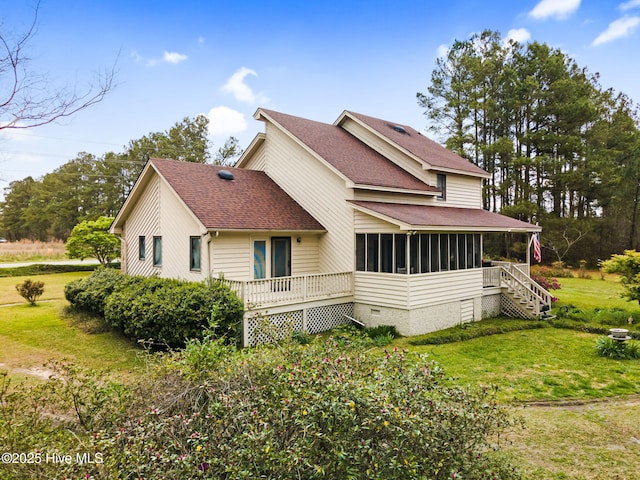 view of side of property with a sunroom, stairway, a lawn, roof with shingles, and a deck