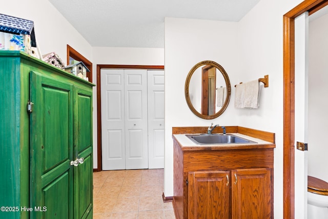 bathroom featuring toilet, vanity, a closet, and tile patterned floors