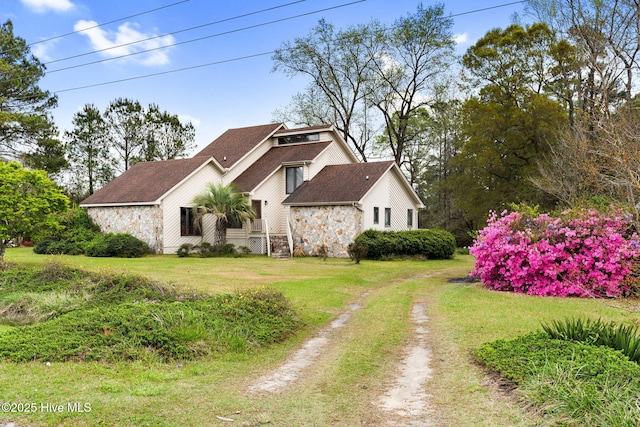 view of property exterior with stone siding, roof with shingles, and a lawn