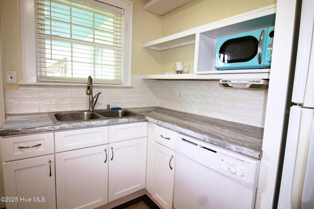 kitchen with a sink, decorative backsplash, white cabinetry, and white dishwasher