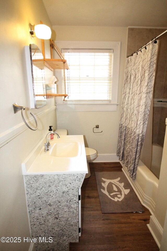 bathroom with baseboards, wood finished floors, toilet, vanity, and shower / tub combo