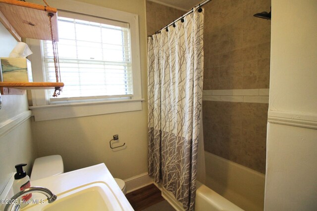 bathroom with a sink, baseboards, toilet, and shower / bath combo with shower curtain