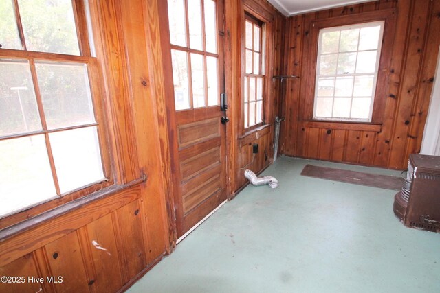 doorway to outside featuring concrete flooring and wooden walls